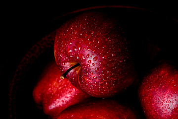 Fresh juicy red apple with droplets of water against dark background