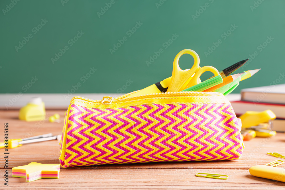 Pencil bag with stationery on desk in classroom