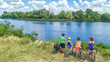 © Iuliia Sokolovska - Family on bikes cycling outdoors, active parents and kids on bicycles, aerial view of happy family with children relaxing near beautiful river from above, sport and fitness concept