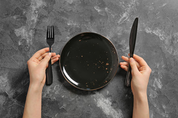 Woman at table with clean plate and cutlery, top view