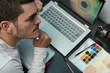 © JoseManuel - Top view of designer thinking on the workplace hold the electronic work pen. Desktop with laptop, camera, watercolors on a dark table.