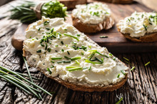 Close-up Of Bread Slice With Traditional Slovak Bryndza Spread Made Of Sheep Cheese With Freshly Cut Chives Placed On Rustic Wood