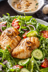 Canvas Print - Portrait close up of grilled chicken and mushrooms with salad, cucumber, cherry tomatoes, red onion, with a creamy mushroom sauce in a separate bowl