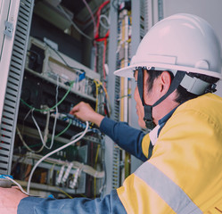 Engineer in yellow uniform, wearing a white safety helmet, checking communication system, big data concept