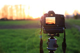 Fototapeta  - Aparat fotograficzny z krajobrazem zachodzącego słońca na obszarze wiejskim.