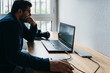 © FranTc - Man working from home on a laptop computer sitting at a desk surfing the internet