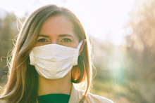 Young Woman Wearing White Cotton Virus Mouth Nose Mask, Nice Backlight Sun Bokeh In Background, Closeup Face Portrait