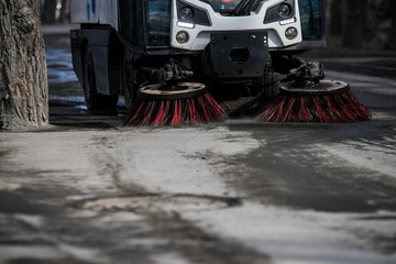 Street cleaner vehicle on the road collecting garbage and junk with brush rotation and vacuum hoover