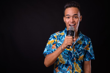 Wall Mural - Portrait of happy young Indian tourist man singing with microphone