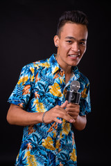 Wall Mural - Portrait of happy young Indian tourist man singing with microphone