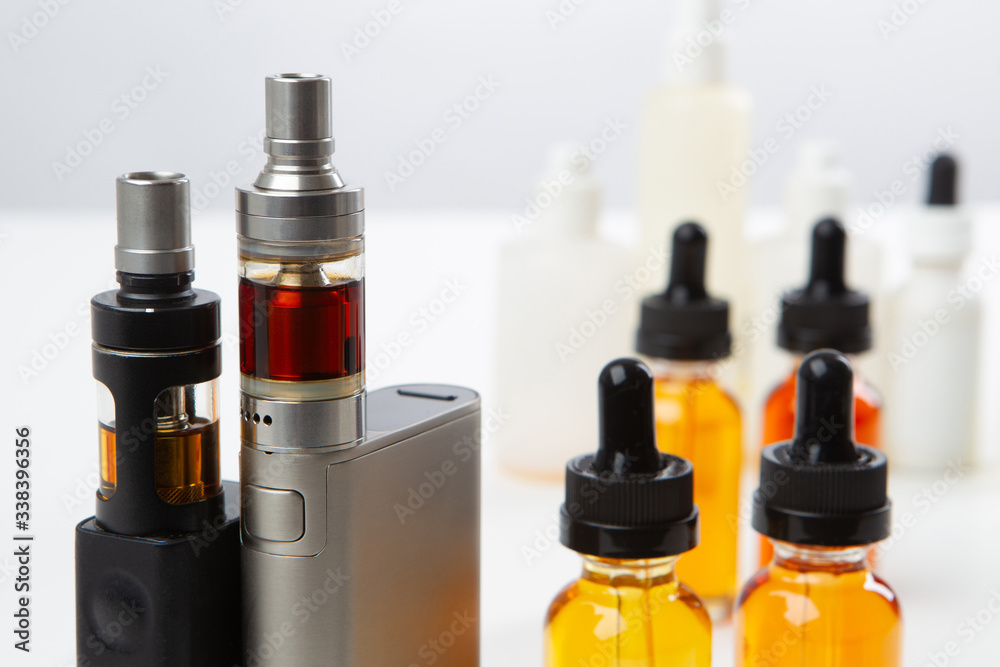 Foto de Stock Vaping. Order an electronic cigarette. Vape device and  bottles of oil. Vaper set. Vaper table. Refueling electronic cigarette.  Concept