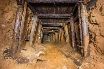 Underground abandoned bauxite ore mine tunnel with wooden timbering