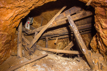 Underground abandoned bauxite ore mine tunnel with collapsed wooden timbering