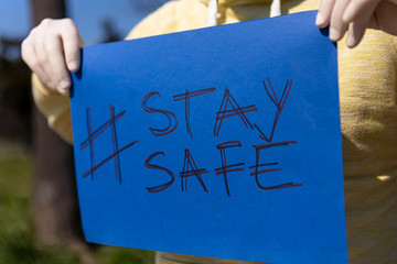 Stay safe sign on blue chroma key paper held by a man in surgical gloves