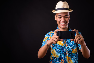 Wall Mural - Portrait of happy young Indian tourist man taking picture with phone