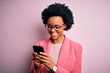 © Krakenimages.com - Young African American afro woman with curly hair having conversation using smartphone with a happy face standing and smiling with a confident smile showing teeth