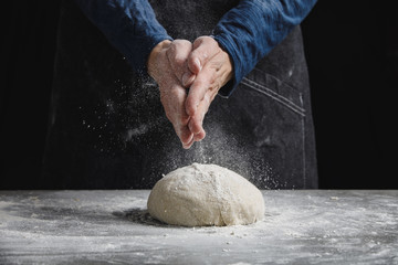 Wall Mural - Thin male hands knead the dough for bread, pasta or pizza, close up. Closeup hand of chef baker kneading a dough. Male chef clapping hands with flour in kitchen 