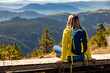 Female hiker with backpack sitting on top of the mountain and enjoying the view during the day.