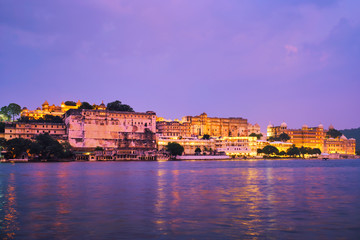 Fototapete - View of famous romantic luxury Rajasthan indian tourist landmark - Udaipur City Palace in the evening twilight with dramatic sky - panoramic view. Udaipur, India