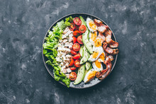 Cobb Salad With Chicken, Avocado, Tomatoes, Eggs, Bacon And Cheese With Sauce On A Black  Table Top View