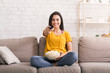 © Prostock-studio - Stay home entertainments. Lovely girl with popcorn watching TV on sofa in living room