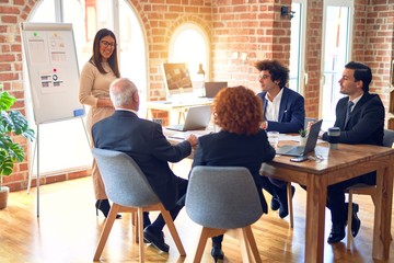 Sticker - Group of business workers smiling happy and confident in a meeting. Working together looking at presentation using board and charts at the office.