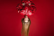 Stock photo studio shot of a fashionable girl in red leather jumpsuit or overall hanging upside down and making duck face. Isolated on red background.