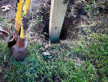 Building New Privacy Fence In Progress: Wooden Post In Hole Ready For Concrete Foundation