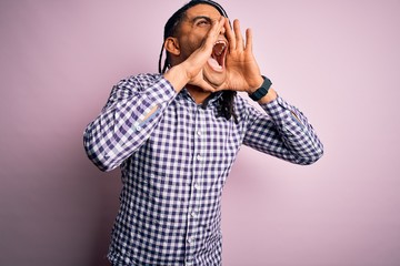 Wall Mural - Young handsome african american afro man with dreadlocks wearing casual shirt Shouting angry out loud with hands over mouth