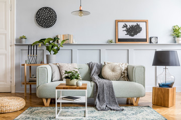 Stylish interior design of living room with modern mint sofa, wooden console, cube, coffee table, lamp, plant, mock up poster frame, pillows, plaid, decoration and elegant accessories in home decor.