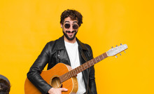 Young Musician Man Looking Happy And Goofy With A Broad, Fun, Loony Smile And Eyes Wide Open With A Guitar, Rock And Roll Concept