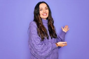 Wall Mural - Young beautiful woman wearing casual turtleneck sweater standing over purple background Inviting to enter smiling natural with open hand