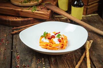 Wall Mural - Side view closeup on italian cuisine dish pasta with tomatoes, mozzarela cheese and basil leaves on the dark wooden table, horizotnal format