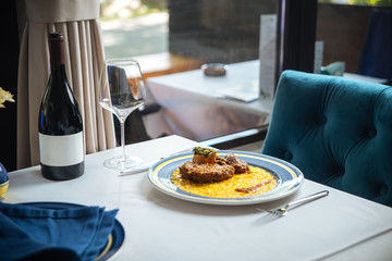 Wall Mural - Italian cuisine dish Ossobuco Alla Milanese with veal stew and risotto on the white table with a bottle of wine, side view