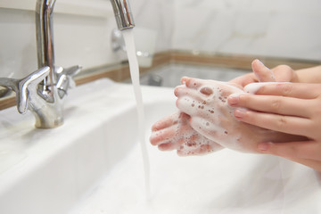 Cropped image of little boy and his mother washing hands with soap