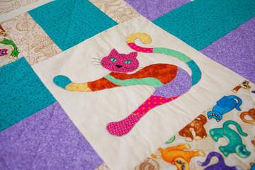 A handmade patchwork quilt repeating square pattern with the image of cat in the middle