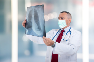 Masked doctor holding a lung radiography, coronavirus and pneumonia concept