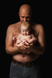 father holds a newborn son in his arms and kisses him. Bald man and a 4 month old baby on a black background