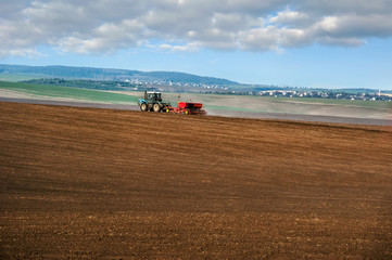 Wonderful panoramic view of land, tractor with seeder, sowing time in spring