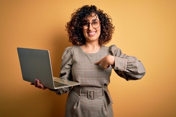 Sticker - Beautiful arab businesswoman wearing glasses working using laptop over yellow background with surprise face pointing finger to himself