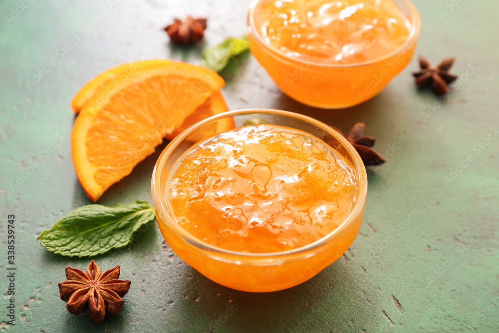 Bowl of orange jam on color background