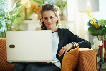 happy female checking website on laptop while sitting on couch