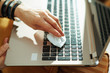 © Alliance - Closeup on woman wiping laptop with cleaning cloth