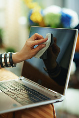 stylish woman wiping laptop display with cleaning cloth