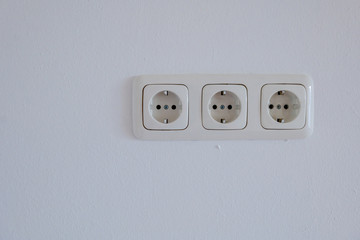 Real triple European socket or outlet Type F on white painted plaster interior wall. 