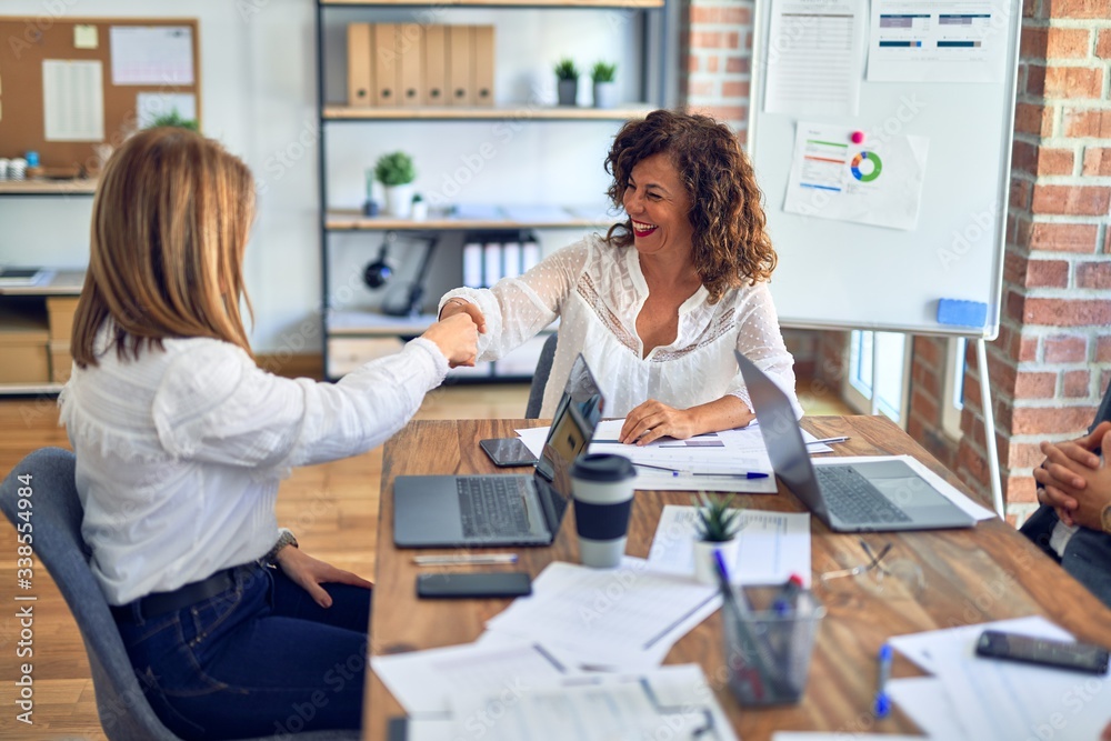 Two middle age beautiful businesswomen smiling happy and confident ...