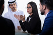 © Moez - Arab attractive businesswoman, teacher or mentor coach speaking to people, Arabic woman in glasses teaching audience at training seminar, female business leader speaker talking at meeting.