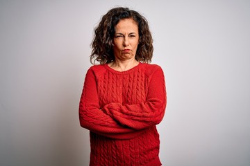 Middle age brunette woman wearing casual sweater standing over isolated white background skeptic and nervous, disapproving expression on face with crossed arms. Negative person.