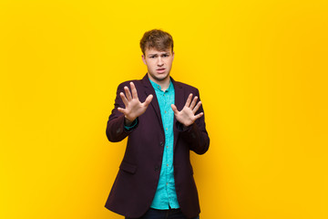 Wall Mural - young blonde man feeling terrified, backing off and screaming in horror and panic, reacting to a nightmare isolated against flat wall