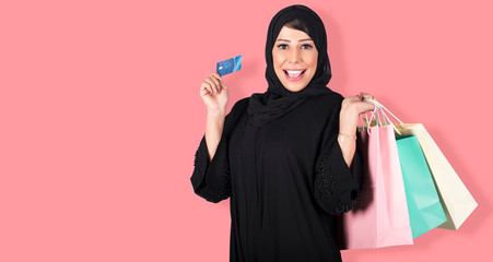 Wall Mural - Arabic excited screaming young woman standing isolated over pink background looking camera holding shopping bags and credit card.